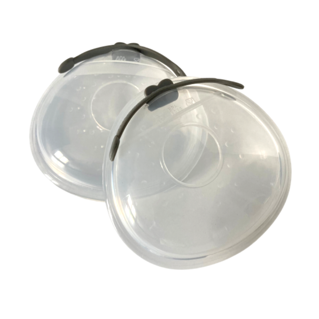Two clear silicone milk shells with a black clip and a case, designed for catching breast milk during feeding.